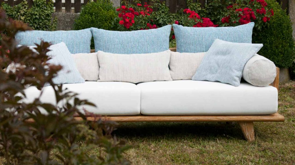 Sofa COMO im Garten von vorne fotografiert; linke Armlehne durch Strauch verdeckt